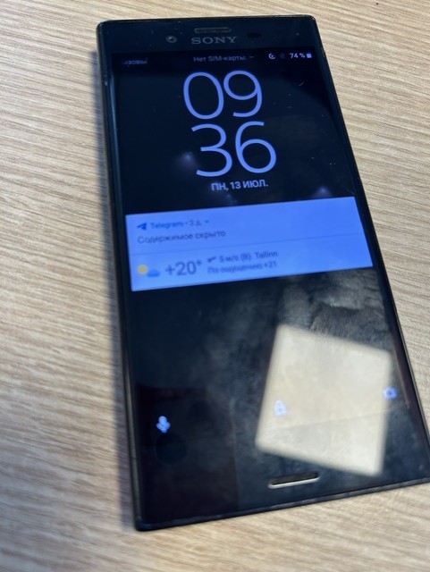 Must nutitelefon kuvab ekraanil kella 09:36 ja teavitusi, asetseb heledal puitpinnal.