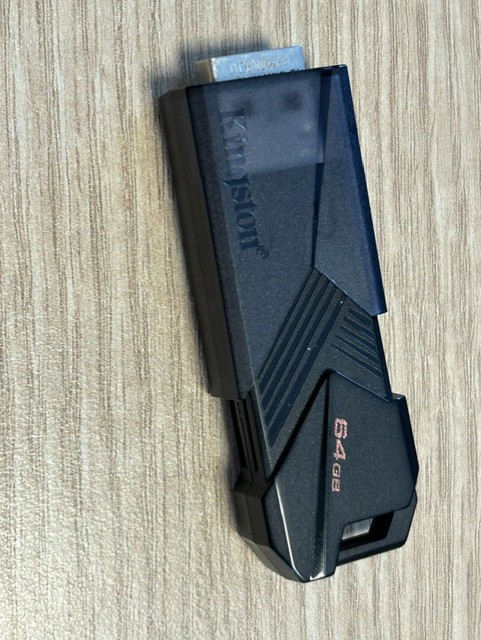 Must Kingstoni 64 GB USB-mälupulk heledal puidust pinnal.