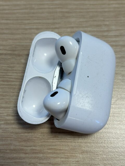 Valge avatud AirPodside laadimiskarp kahe AirPodiga puidust pinnal.